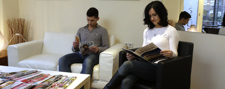 Ein Herr und eine Dame sitzen im Wartebereich und lesen Zeitschriften